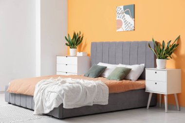 Güzel bir yatak odası, rahat bir yatak odası, çekmeceler, komodin ve çiçek.