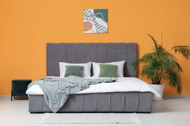 Güzel yatak odası, rahat yatak, puf, resim ve çiçek.