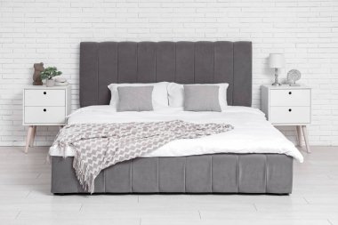 Yatak, lamba, yastık ve komodinli rahat bir yatak odası.