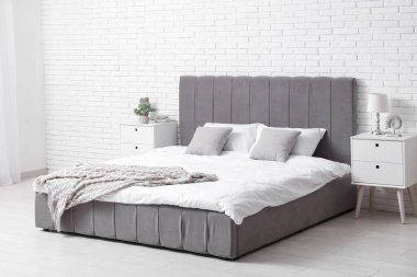 Yatak, lamba, yastık ve komodinli rahat bir yatak odası.