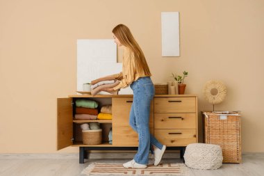 Güzel genç bir kadın evdeki dolabına temiz giysiler koyuyor.