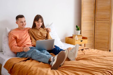 Yatak odasında dizüstü bilgisayarda film izleyen genç çift.