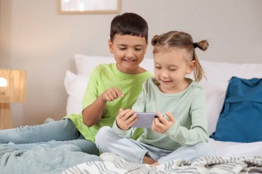 Cep telefonlu şirin çocuklar evlerinde video oyunları oynuyorlar.