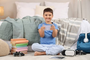 Evde video oyunları oynayan, aletleri ve kitapları olan sevimli, mutlu küçük bir çocuk.