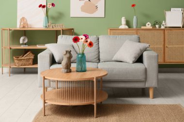 Vazodaki güzel Gerbera çiçekleri ve oturma odasının iç tarafındaki masada duran heykelcikler.