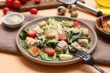 Lezzetli tavuklu Sezar salatası ve turuncu arka planda bir kase sos, yakın plan.