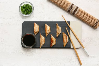 Kızarmış Japon gyozası ve beyaz arka planda bir kase soya sosu.