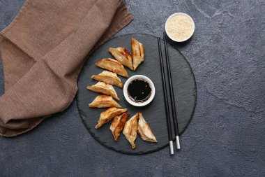 Koyu arkaplanlı soya sosu ve susam tohumlu kızarmış Japon gyozası.