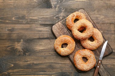 Tahta arka planda susam tohumlu lezzetli simit kesme tahtası