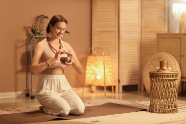 Tibet şarkı kasesiyle evde meditasyon yapan genç ve güzel bir kadın.