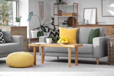 Gri kanepeleri ve kahve masasında taze limonları olan modern oturma odasının içinde.