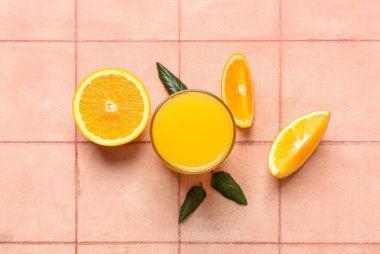 Bir bardak portakal suyu ve bej kaplamalı yapraklar.