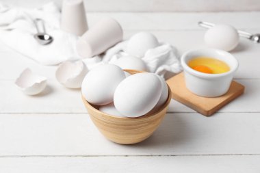 Beyaz ahşap masada çiğ tavuk yumurtası ile kase