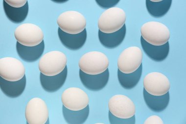 Mavi arka planda bir sürü çiğ tavuk yumurtası