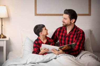 Babası ve küçük oğlu yatak odasında masal okuyorlar.