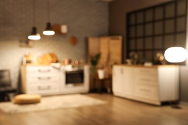 Tezgahlı bulanık mutfak manzarası, katlanan ekran ve akşamları parlayan lambalar