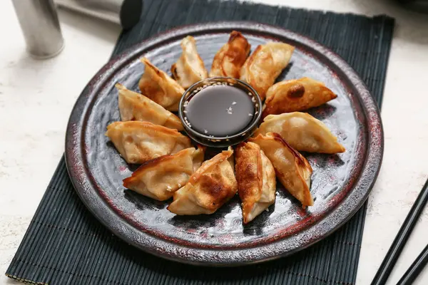 Kızarmış Japon gyoza tabağı ve beyaz arka planda soya sosu.
