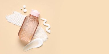 Bir şişe mikiler suyu ve bej arka planda krema örnekleri.