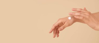 Cilt kremi sürmüş kadın elleri bej arkaplan ve metin için boşluk