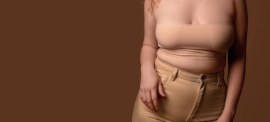 Genç vücut pozitifliği olan kahverengi arka planda mesaj için yeri olan bir kadın