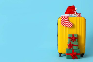 Noel Baba şapkalı çanta, Noel çorabı ve mavi arka planda hediyeler.