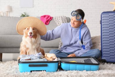 Avustralyalı çoban köpeği olan genç çocuk eve gitmek için bavul hazırlıyor.