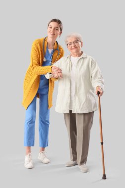 Uzaktan kumandalı yaşlı kadın ve hemşire el ele tutuşuyorlar.