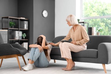 Ofiste üzgün genç bir kızla çalışan kadın psikolog.