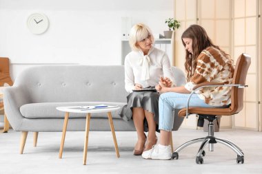 Ofiste el ele tutuşan üzgün genç kız ile kadın psikolog.