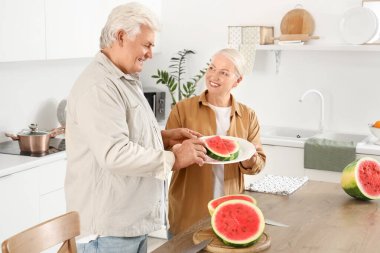 Mutfakta karpuz kesen olgun bir çift.