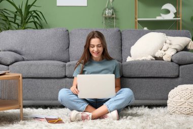 Evde dizüstü bilgisayar kullanan güzel bir kadın.