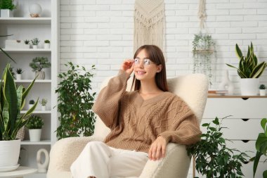 Evdeki çiçeklerin yanındaki beyaz koltukta oturan genç bayan bahçıvan.