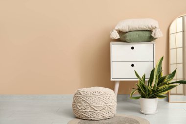 Kahve masası, ev bitkisi, puf ve ayna olan modern oturma odası.