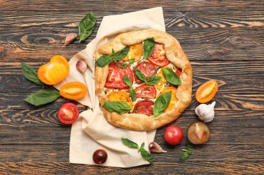 Lezzetli domatesli kompozisyon fesleğen ve ahşap arka planda sarımsak.