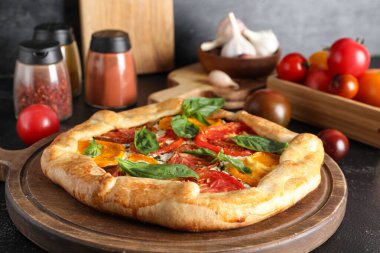 Siyah arka planda fesleğenli lezzetli domates galetesi tahtası.