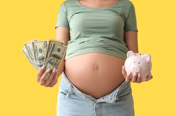 Молодая беременная женщина с деньгами и копилкой на жёлтом фоне, крупным планом. Концепция материнского пособия