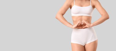 İç çamaşırlı güzel bir kadın elleri açık arkaplanda, mesaj için yeri olan bir kalp yapıyor.