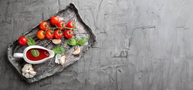 Domates soslu sos kabı ve gri arkaplanda metinler için yeri olan malzemeler.