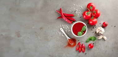 Bir kase domates sosu ve gri arkaplandaki malzemeler metin ve üst görünüm için boşluk