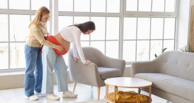 Eşarplı hamile bir kadına masaj yapan olgun bir doğum koçu. 