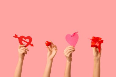 Dekoratif kalpleri olan kadın elleri ve pembe arka planda hediye kutusu. Sevgililer Günü kutlaması