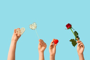 Dekoratif kalpleri olan kadın elleri ve mavi arka planda kırmızı gül. Sevgililer Günü kutlaması