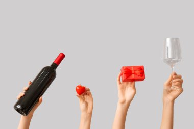 Kalpli kadın eller, hediye kutusu, gri arka planda cam ve şarap şişesi. Sevgililer Günü kutlaması