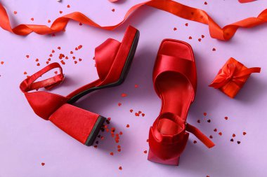 Kırmızı kadın ayakkabılı kompozisyon, hediye kutusu ve renk arka planında Sevgililer Günü kutlaması için dekor.
