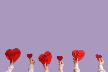 Hediye kutuları ve leylak arkaplanda kalpleri olan kadın elleri. Sevgililer Günü kutlaması