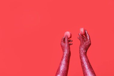 Kırmızı arka planda lezzetli kurabiyeler olan boyalı kadın elleri.