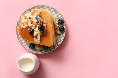 Kalp şeklinde lezzetli gözlemeler, pembe arka planda yabanmersini ve süt. Sevgililer Günü kutlaması