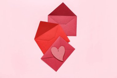 Zarflı kompozisyon ve pembe arka planda kağıt kalp. Sevgililer Günü kutlaması