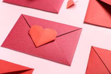 Zarflı kompozisyon ve pembe arka planda kağıt kalp. Sevgililer Günü kutlaması