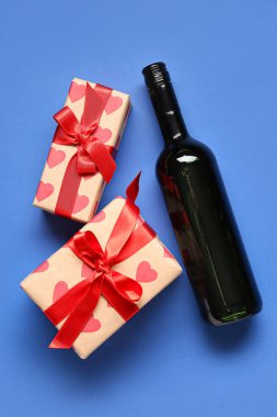 Mavi arka planda hediyeler olan bir şişe şarap. Sevgililer Günü kutlaması